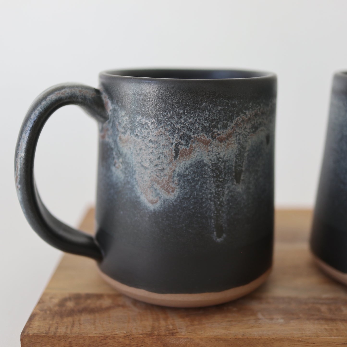 a grey pottery mug on a brown board